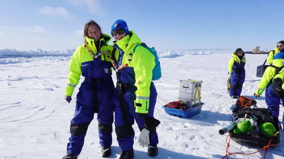 Two researchers standing in the overalls on a large sheet of ice