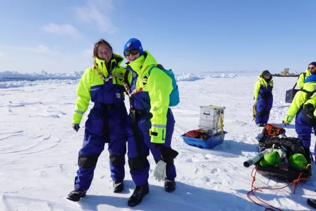 Two researchers standing in the overalls on a large sheet of ice