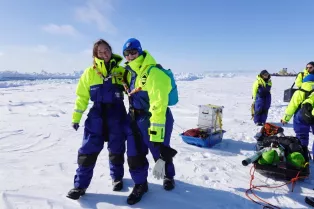 Two researchers standing in the overalls on a large sheet of ice