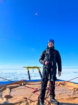 A man standing on a a large boat in the Arctic Ocean